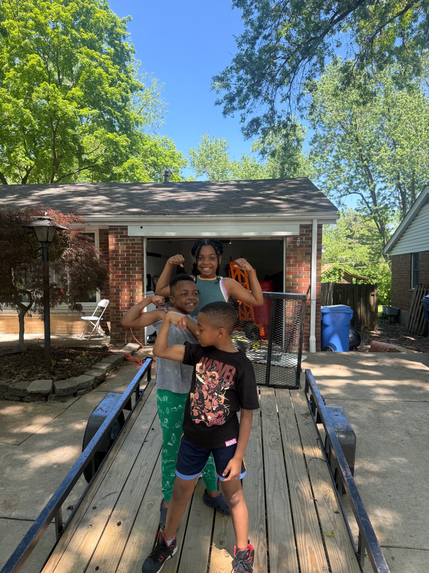 Kids standing on the Jump & Jam equipment trailer in the driveway outside the family garage